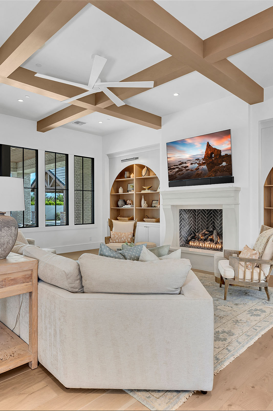 A warm and inviting living room with an arched built-in bookcase, neutral decor, and a stylish fireplace centerpiece.