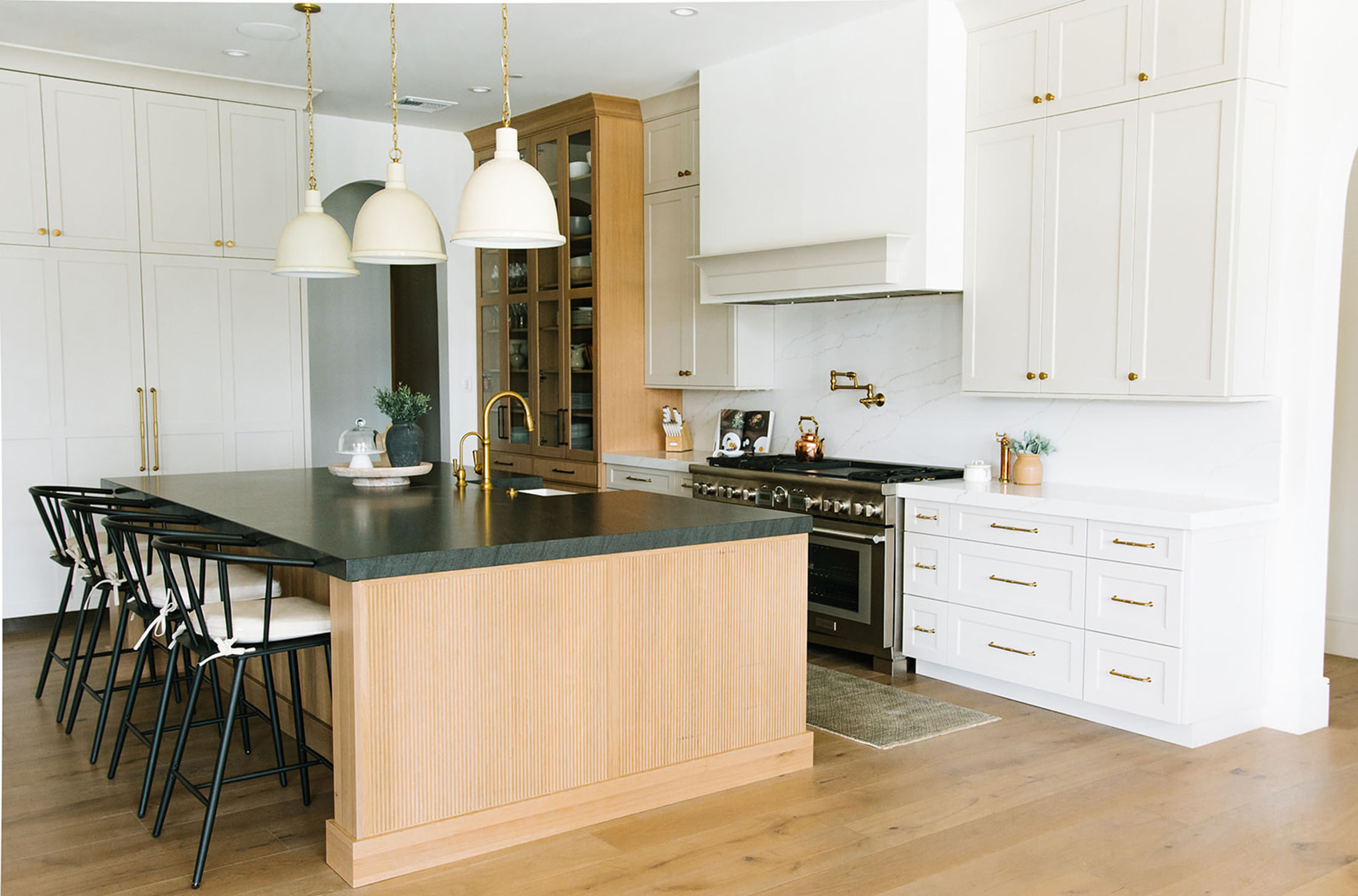 A chef’s dream kitchen with a sleek black island, brass pendant lighting, and custom cabinetry for a high-end look.