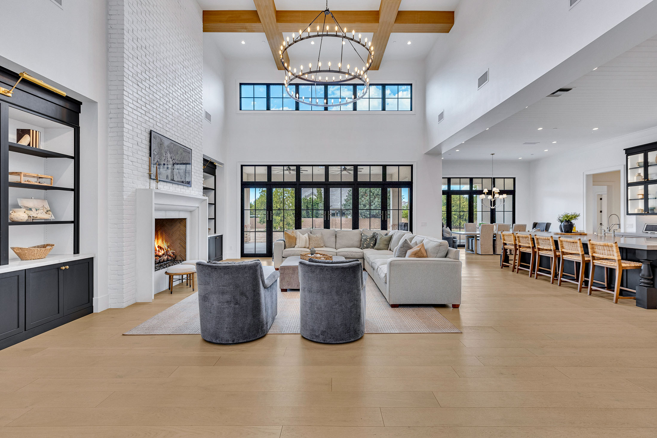 Spacious farmhouse-style kitchen featuring a large island, black pendant lighting, white cabinetry, and an open dining area with industrial accents.