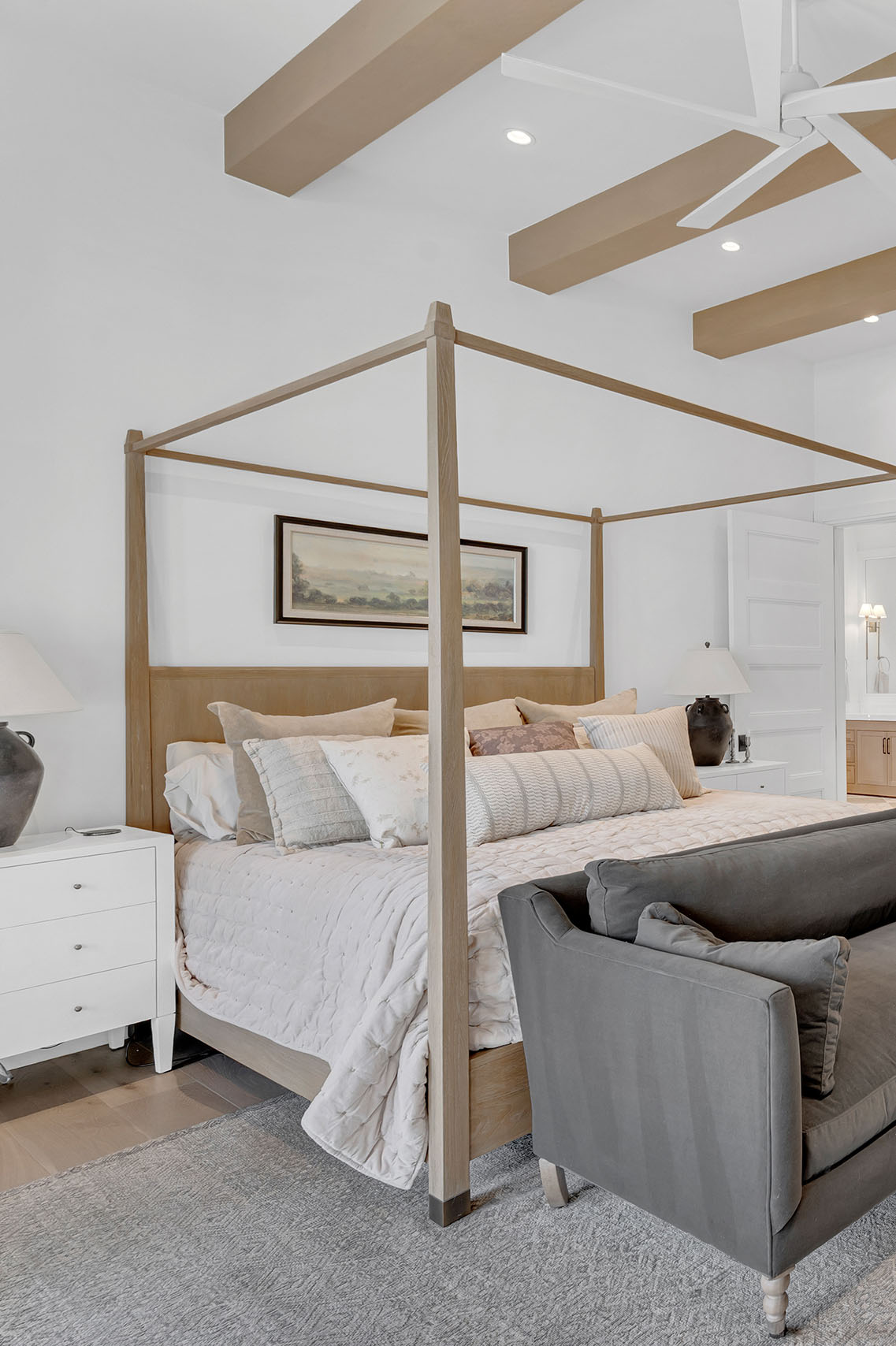 Cozy Bedroom with Four-Poster Bed and Neutral Tones – A serene bedroom with a wooden four-poster bed, neutral bedding, and black ceramic table lamps, creating a warm and inviting atmosphere.