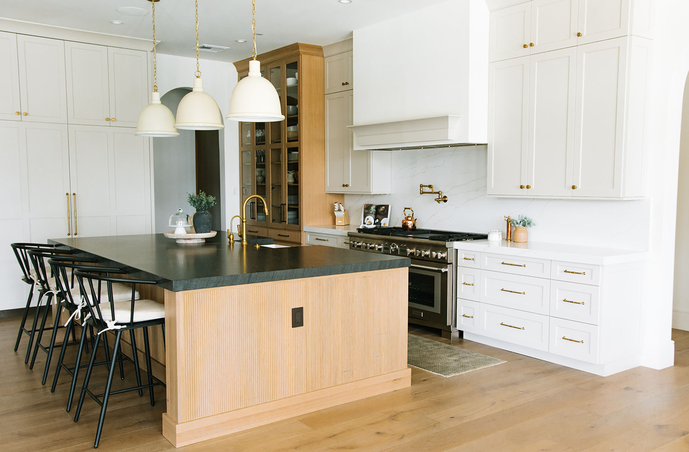 A chef’s dream kitchen with a sleek black island, brass pendant lighting, and custom cabinetry for a high-end look.