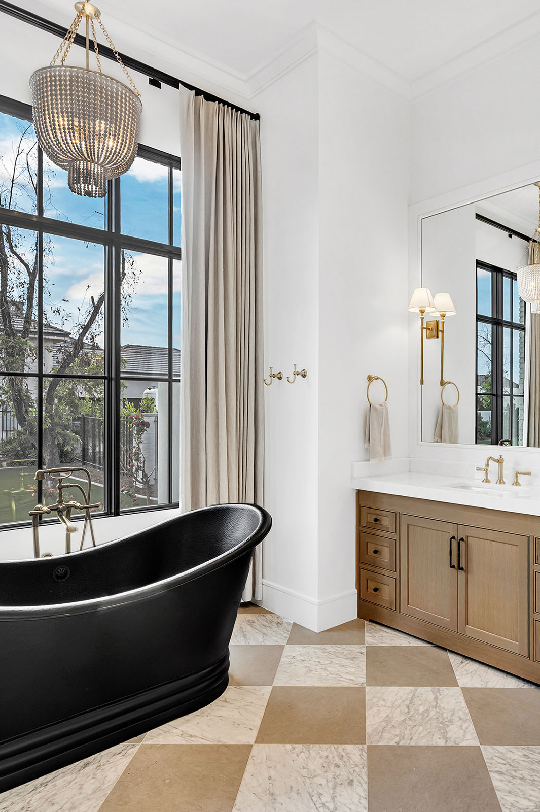 Luxury Bathroom with Black Freestanding Tub and Gold Accents – Elegant bathroom featuring a black freestanding bathtub, gold fixtures, marble checkerboard flooring, and large windows for natural light.