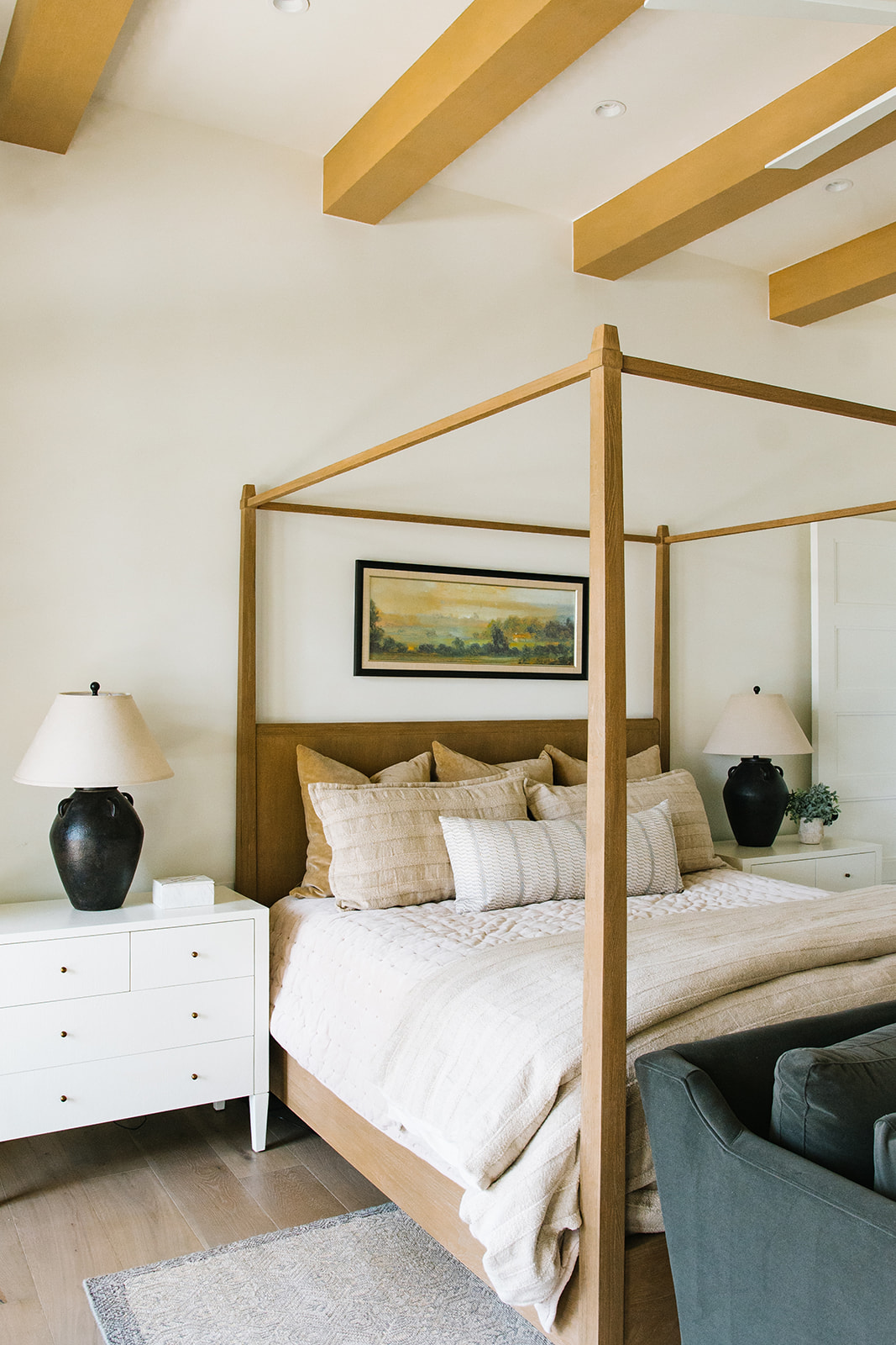 Cozy Bedroom with Four-Poster Bed and Neutral Tones – A serene bedroom with a wooden four-poster bed, neutral bedding, and black ceramic table lamps, creating a warm and inviting atmosphere.