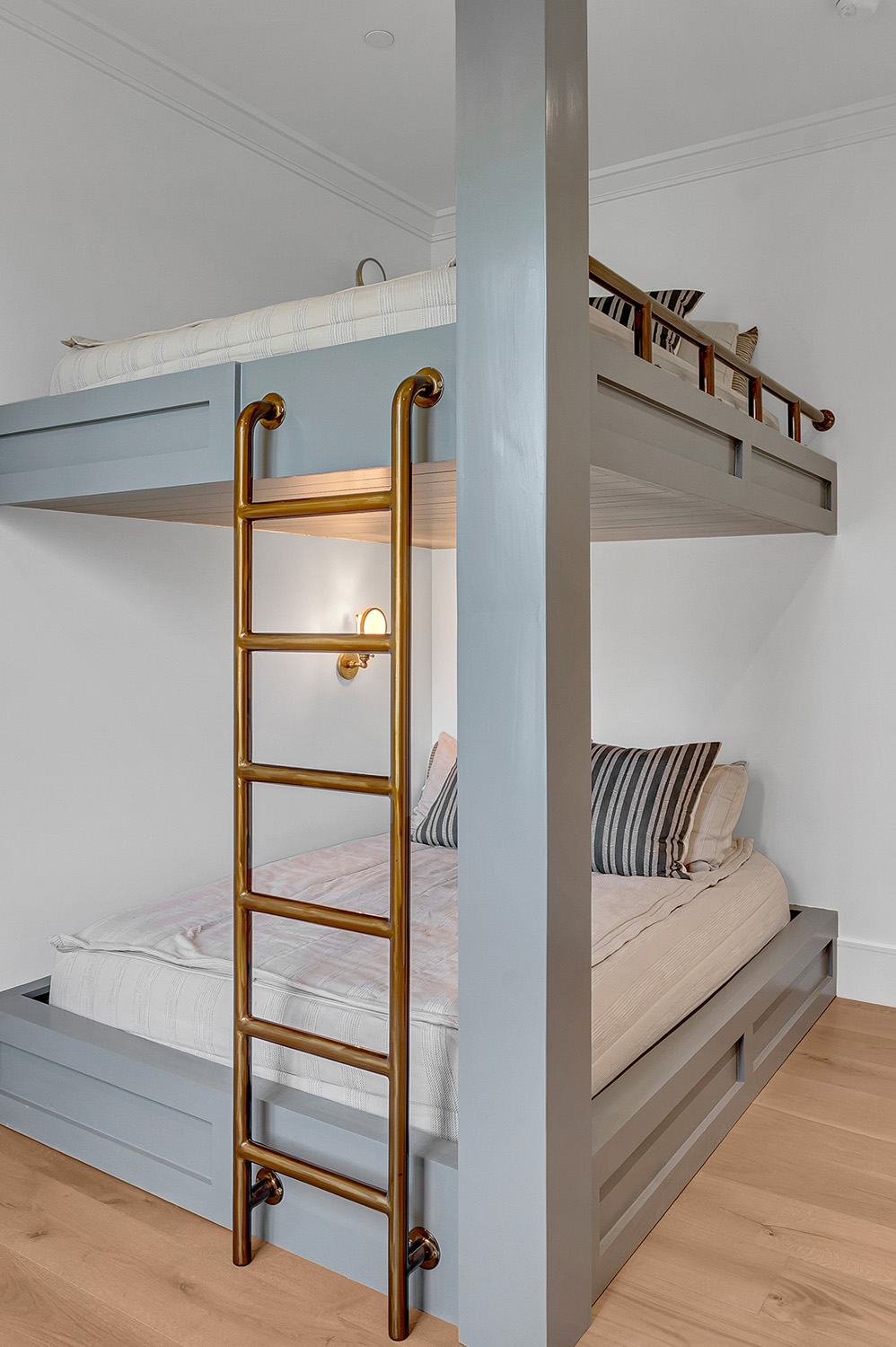 Custom Built-in Bunk Beds with Brass Ladder – Stylish built-in bunk beds painted in muted green, featuring a brass ladder and cozy striped pillows for a modern farmhouse bedroom design.