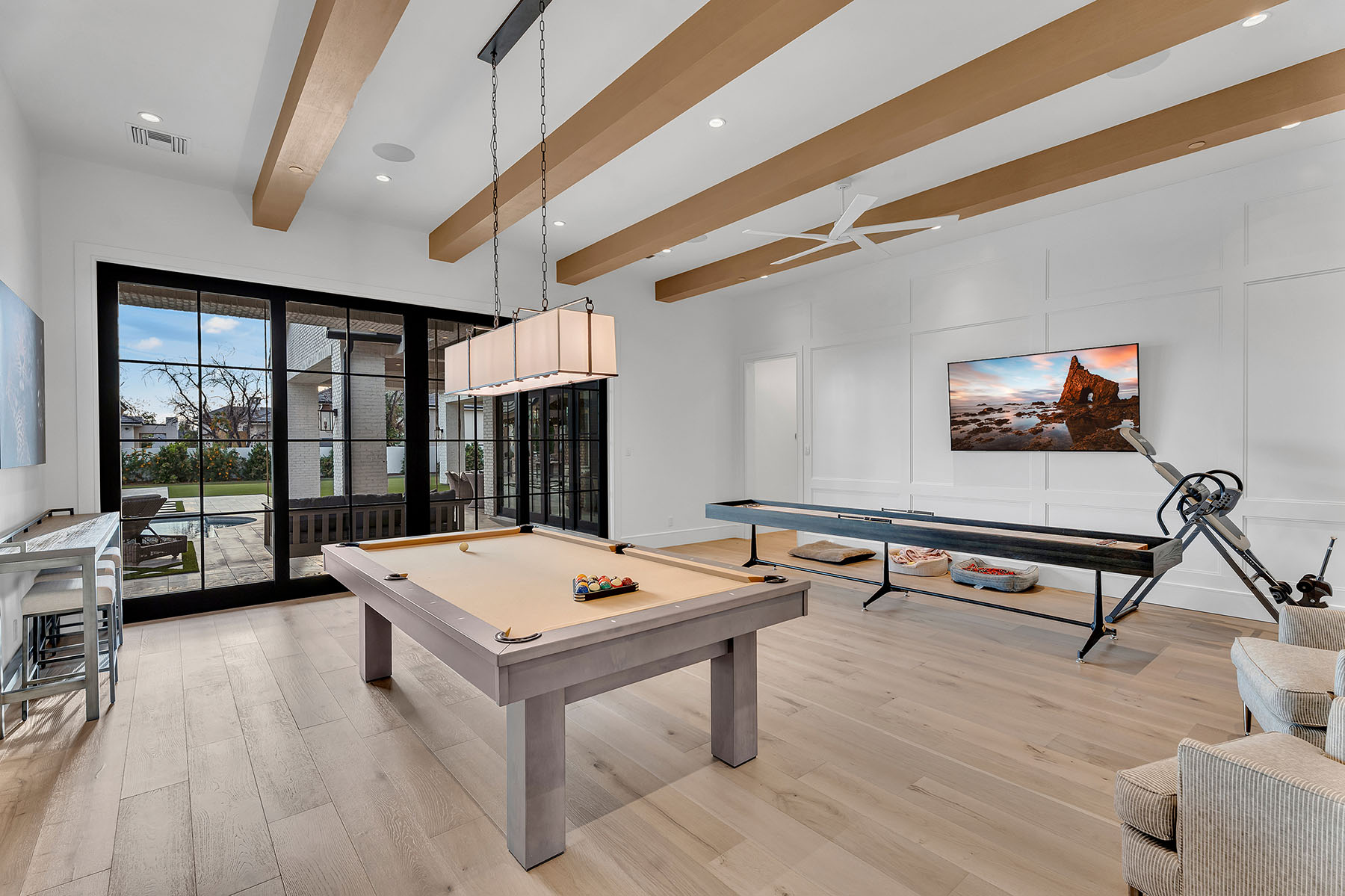Sports-Themed Entertainment Room with Custom Cabinetry – A modern entertainment space featuring a large flat-screen TV, custom-built white cabinetry, and framed sports jerseys. Glass-encased football helmets on display add to the sports-themed decor.
