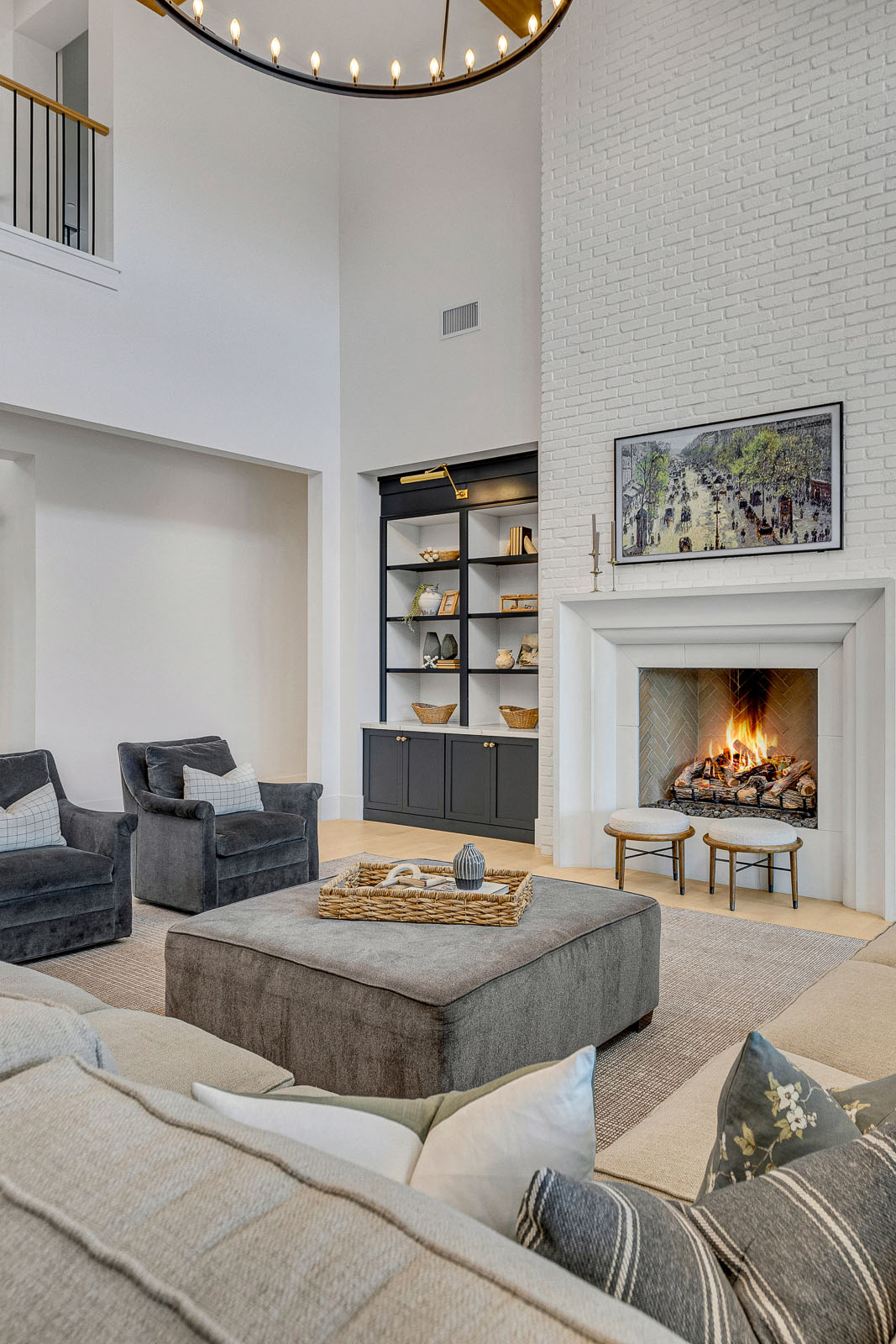 A sophisticated living area featuring a grand white brick fireplace, dark built-in bookcases, and plush seating.