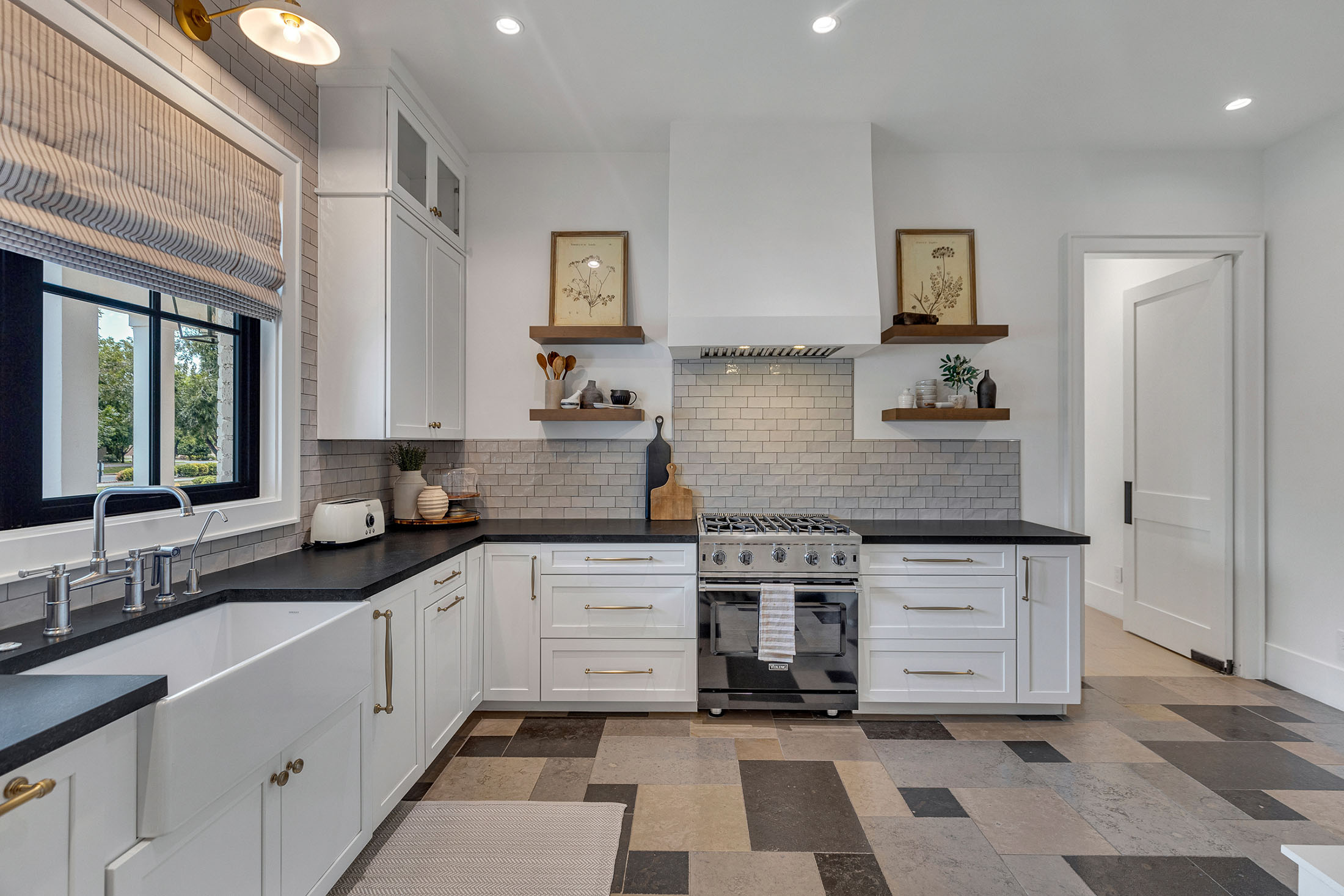 Luxury Kitchen with Custom Shelving and Modern Design – A sleek and stylish kitchen featuring white cabinetry, black countertops, subway tile backsplash, and elegant brass fixtures, seamlessly blending function and design.