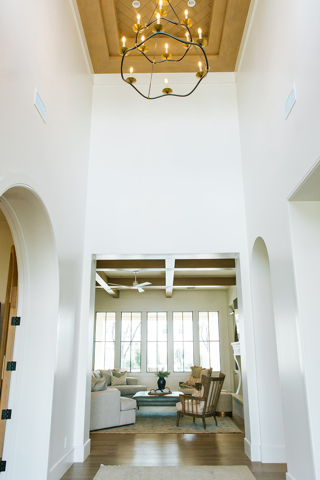 Grand Entryway with High Ceilings and Statement Chandelier – Stunning foyer with arched doorways, tall ceilings, and a contemporary chandelier, leading into a bright and airy living space.