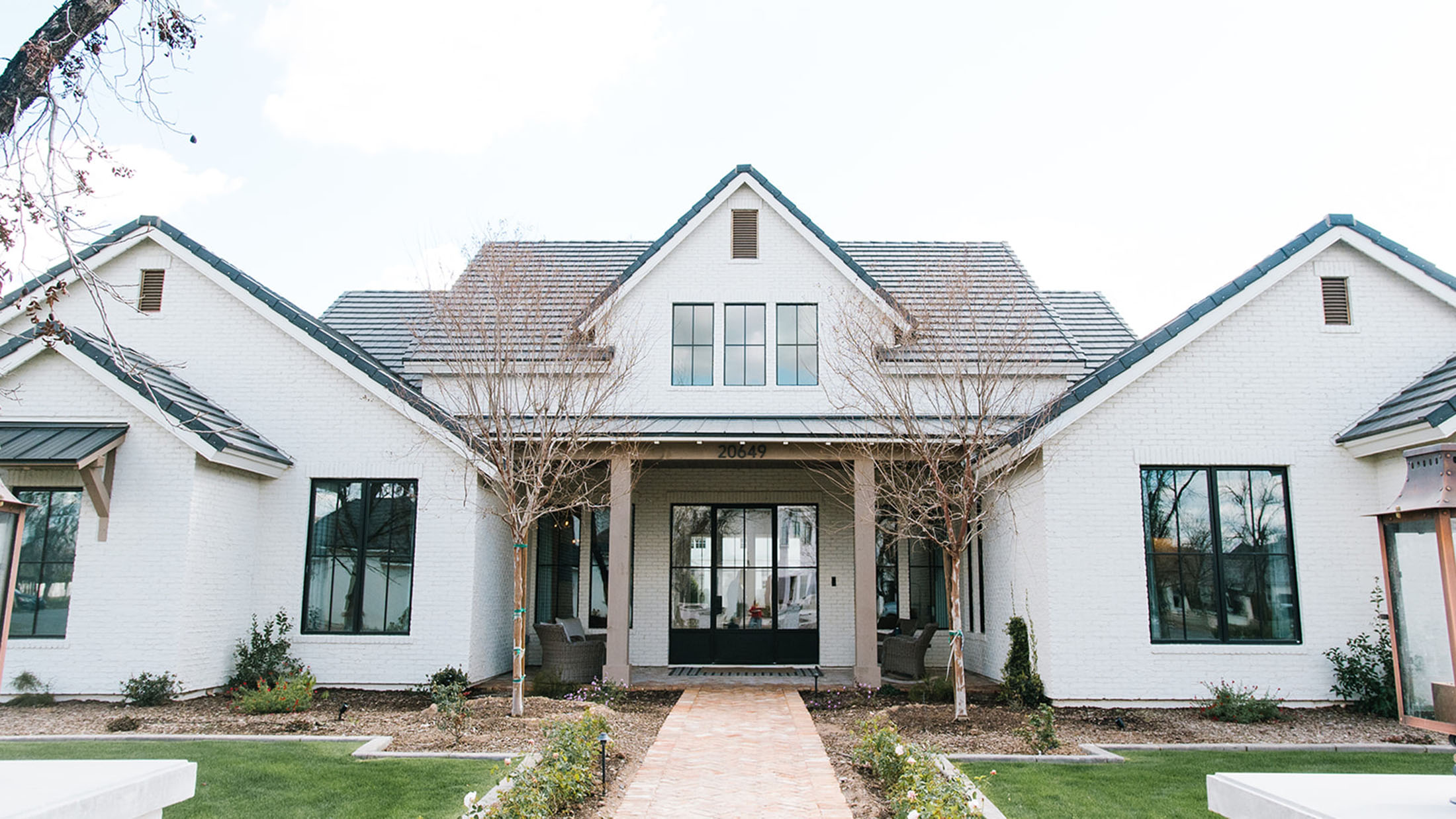 Modern exterior with white brick facade and black-framed windows – A stunning modern home featuring a white brick exterior, black-framed windows, and a welcoming front porch with symmetrical landscaping.