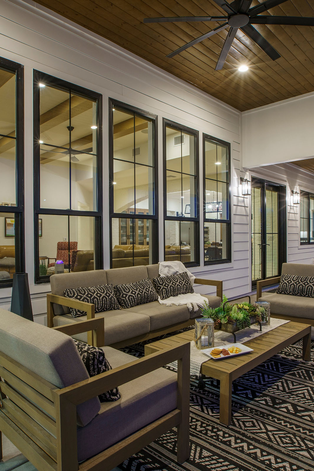 Cozy outdoor living space with wooden ceiling and modern seating – A warm and inviting outdoor lounge area featuring wooden ceilings, large windows, modern furniture, and ambient lighting for ultimate relaxation.