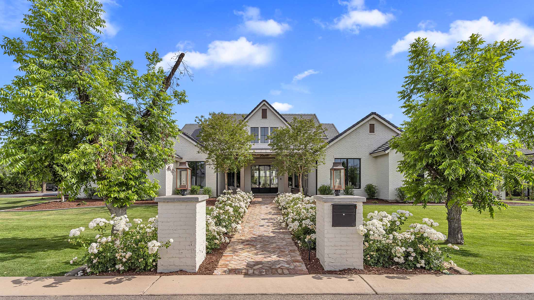Modern exterior with white brick facade and black-framed windows – A stunning modern home featuring a white brick exterior, black-framed windows, and a welcoming front porch with symmetrical landscaping.