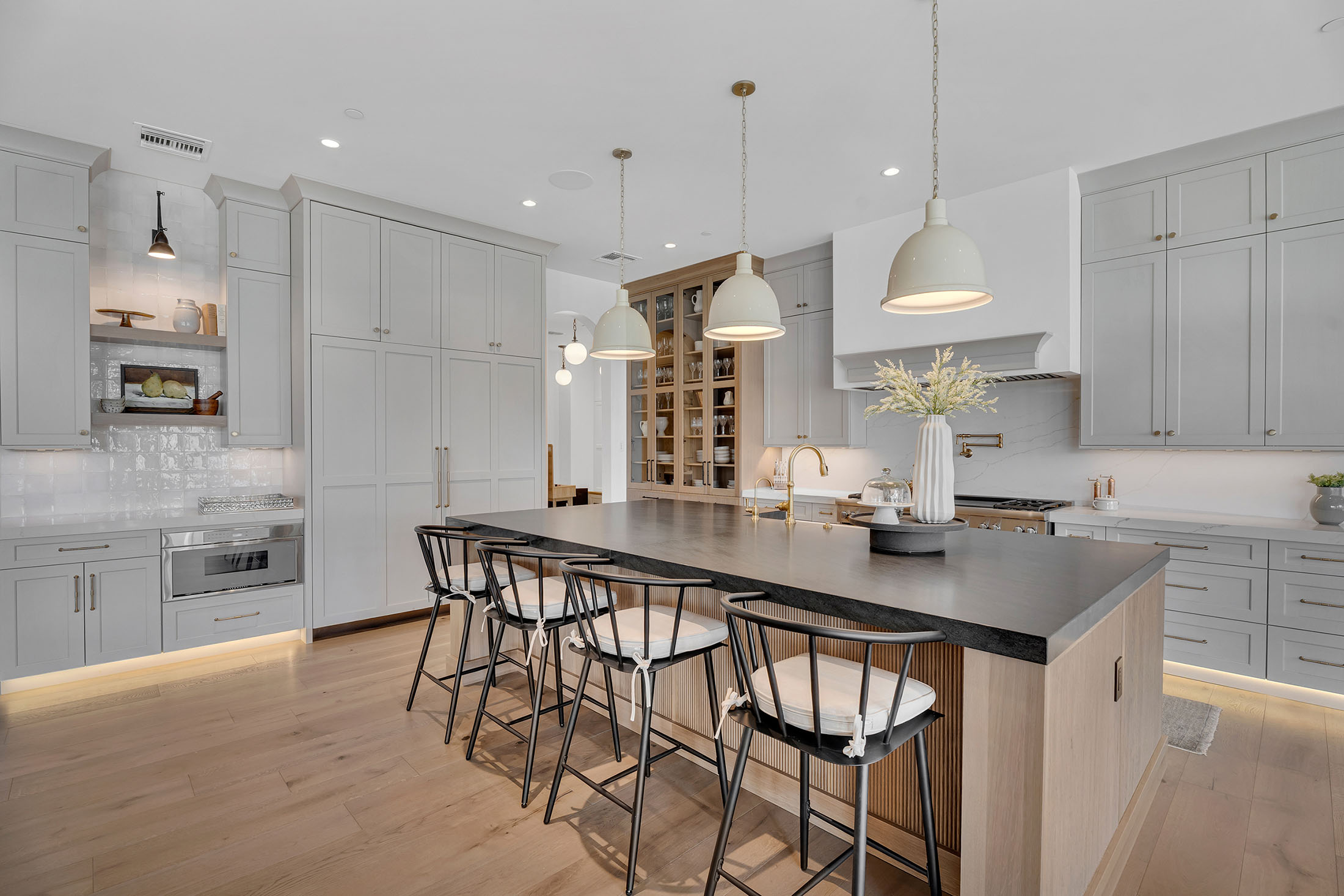 A chef’s dream kitchen with a sleek black island, brass pendant lighting, and custom cabinetry for a high-end look.