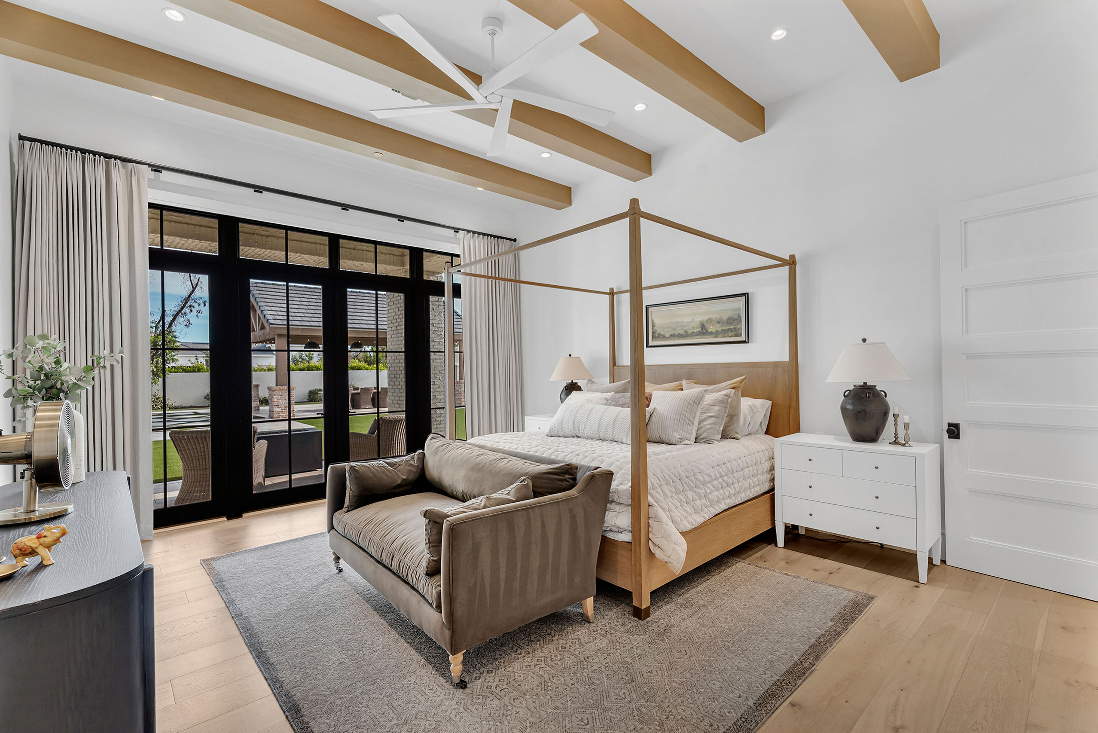 Serene master bedroom with wood-beamed ceilings and luxurious neutral decor.